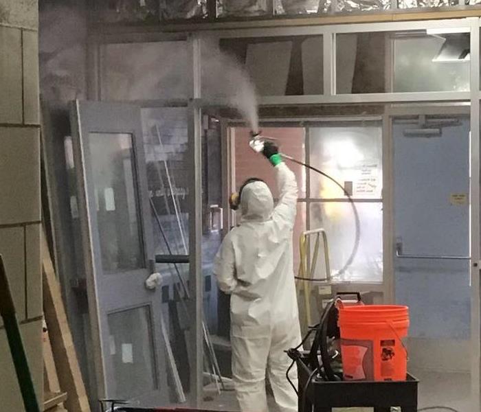 men in ppe fogging disinfectant in a building